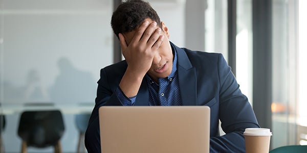 Distrought victim of scam looking at laptop